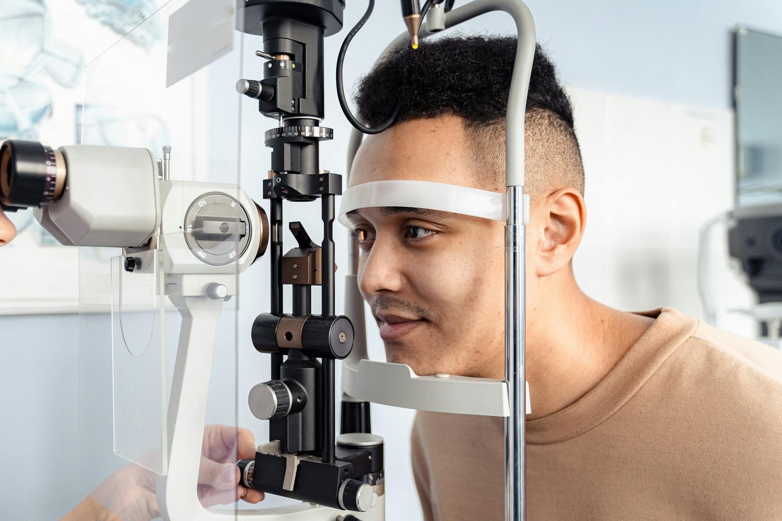 A young man having an eye examination with a slit lamp in a clinic setting.
